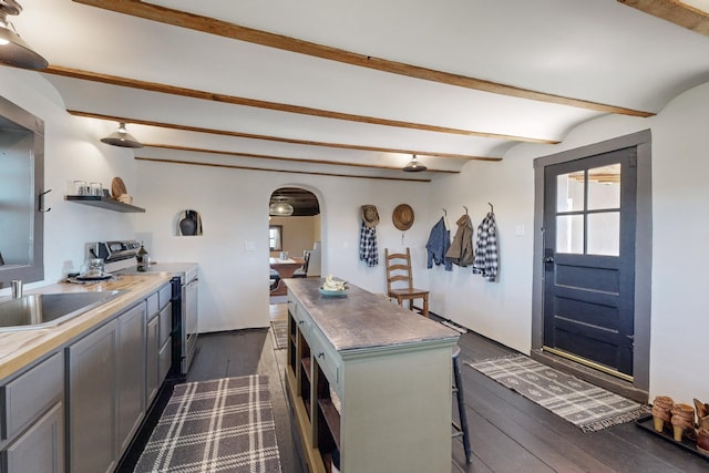 54 County Road B40A, Ribera, NM 87560 - kitchen with stainless steel range with electric cooktop, open shelves, arched walkways, beam ceiling, and dark wood finished floors