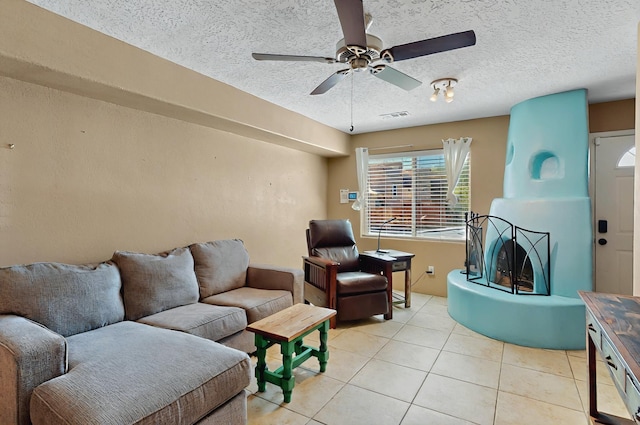 living room featuring light tile patterned flooring, ceiling fan, visible vents, and a textured ceiling