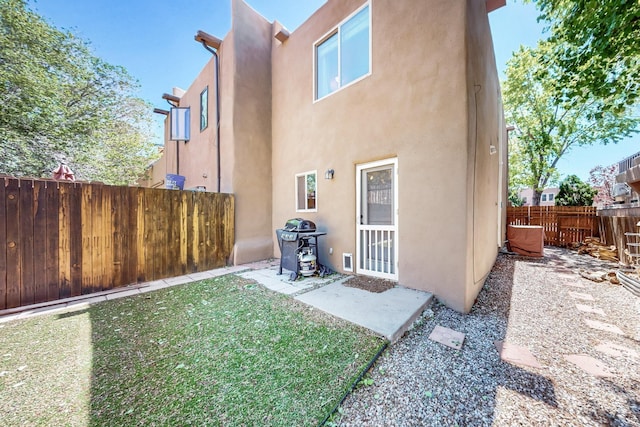 rear view of property with a yard, a fenced backyard, and stucco siding