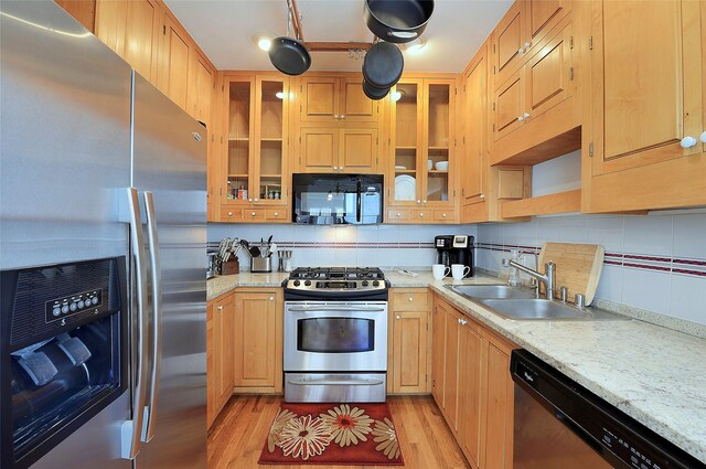 511 Armijo Unit C, Santa Fe, NM 87501 - kitchen featuring appliances with stainless steel finishes, a sink, light wood-style flooring, tasteful backsplash, and glass insert cabinets