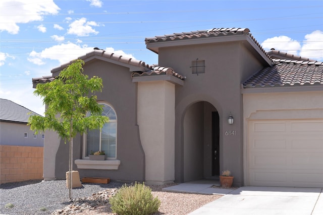 mediterranean / spanish home with an attached garage, stucco siding, driveway, and a tile roof