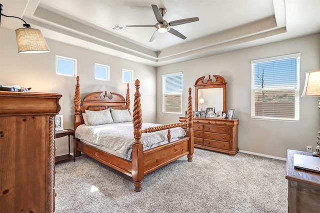 bedroom featuring ceiling fan, carpet, baseboards, a tray ceiling, and visible vents