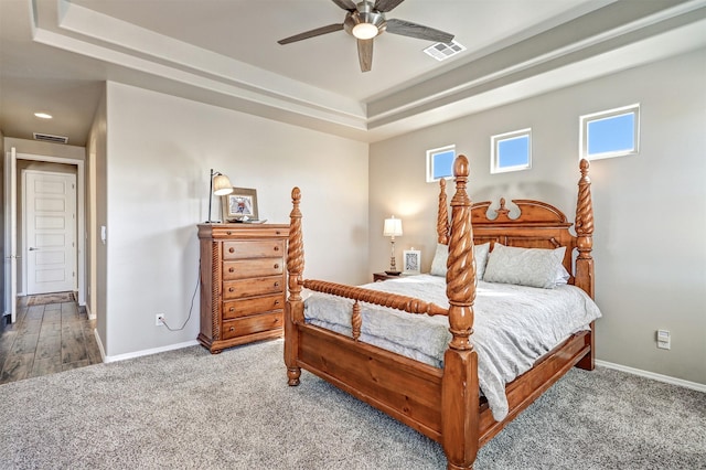 carpeted bedroom featuring baseboards, visible vents, and a raised ceiling