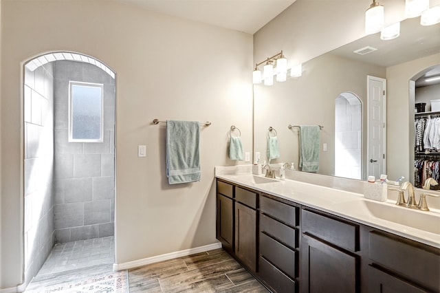 6841 Cleary Loop NE, Rio Rancho, NM 87144 - full bathroom with wood finished floors, double vanity, tiled shower, a spacious closet, and baseboards