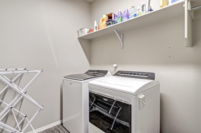 laundry area featuring baseboards, laundry area, washing machine and dryer, and wood finished floors