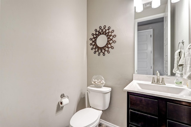 half bath with toilet, baseboards, visible vents, and vanity