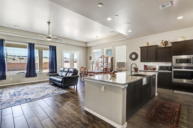 kitchen featuring dark wood-style flooring, stainless steel appliances, visible vents, and a sink