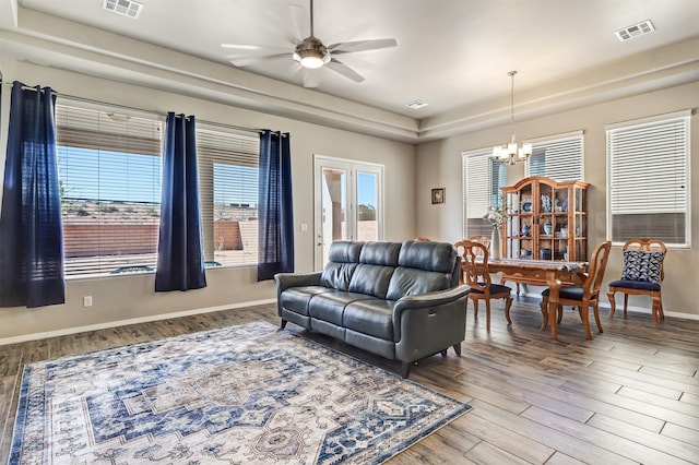 living area with visible vents, baseboards, ceiling fan with notable chandelier, and wood finished floors