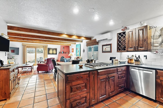 kitchen with a wall unit AC, a textured ceiling, dark countertops, appliances with stainless steel finishes, and a peninsula