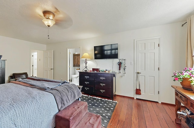 bedroom featuring baseboards, wood-type flooring, and ensuite bath