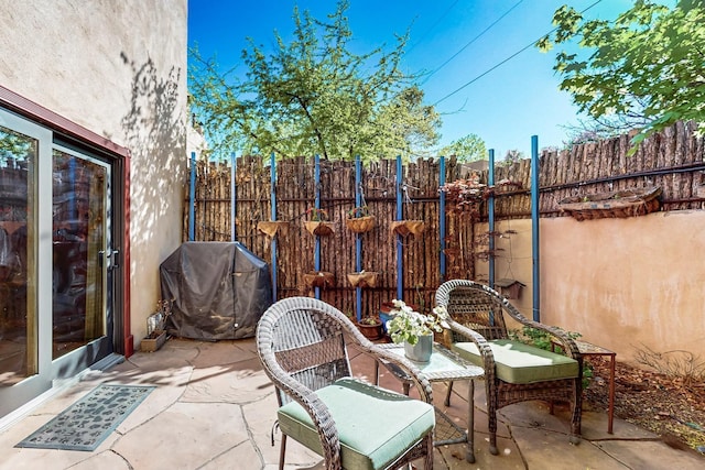 view of patio featuring fence and a grill