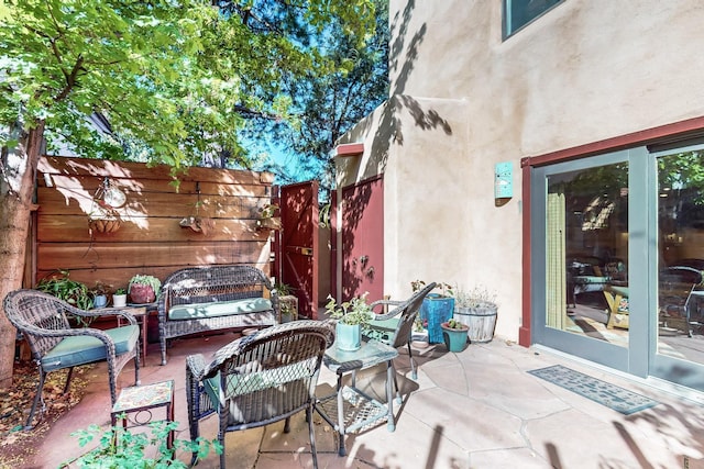 view of patio with an outdoor living space, fence, and french doors