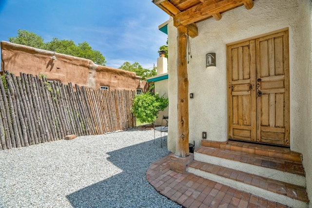 entrance to property with fence and stucco siding