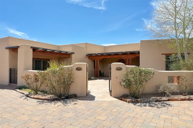 pueblo-style home with a gate and a fenced front yard