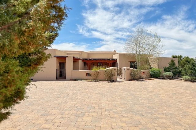 pueblo-style home with a gate, a fenced front yard, and stucco siding