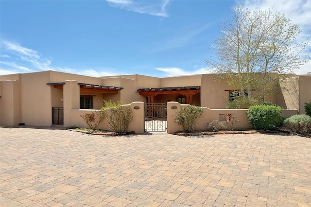 adobe home featuring a gate and a fenced front yard