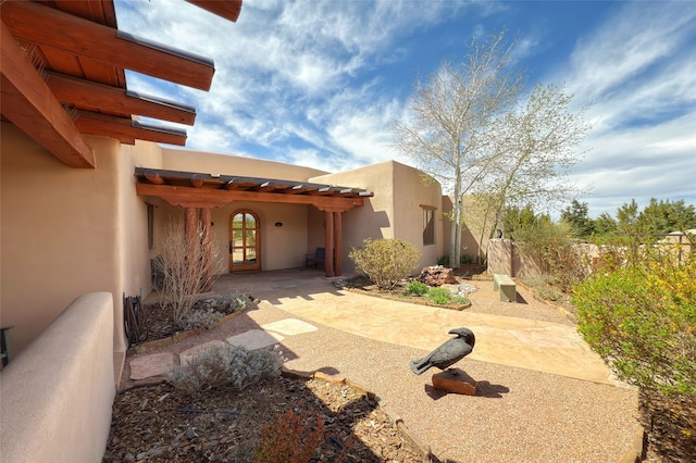 view of exterior entry with fence and a patio area