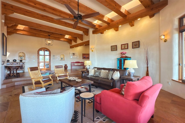 living area with arched walkways, a towering ceiling, ceiling fan, and beamed ceiling