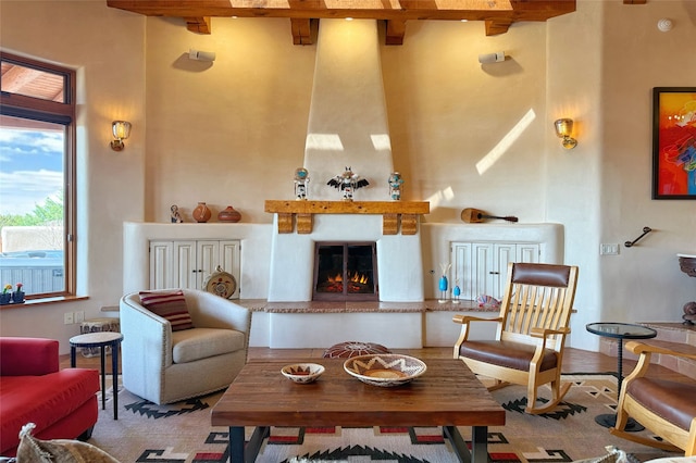 sitting room featuring a large fireplace, a high ceiling, and beam ceiling