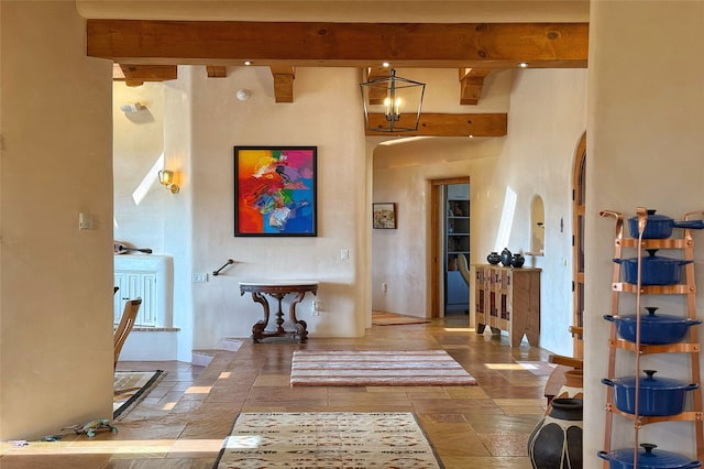 entryway featuring arched walkways, a high ceiling, and beam ceiling
