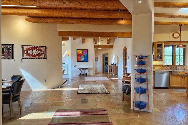 foyer with arched walkways, beamed ceiling, and stone tile floors
