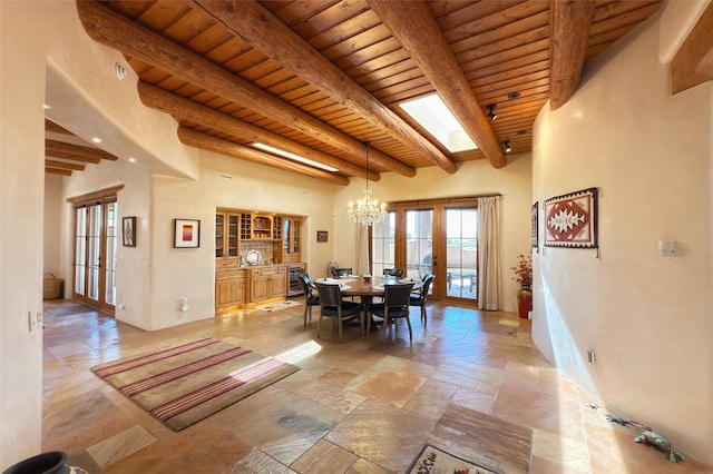 dining space with wood ceiling, beamed ceiling, french doors, and stone tile flooring