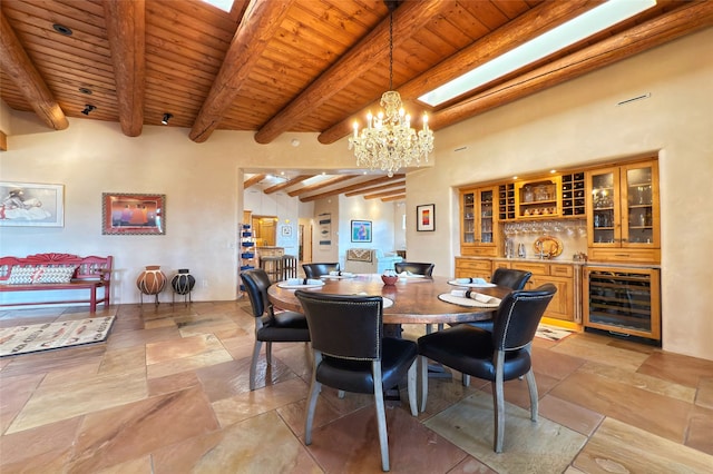 dining space with wooden ceiling, beamed ceiling, stone tile flooring, beverage cooler, and bar area