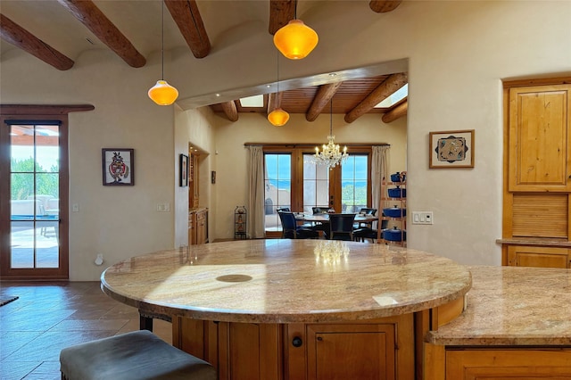 kitchen with a healthy amount of sunlight, hanging light fixtures, beamed ceiling, and a notable chandelier