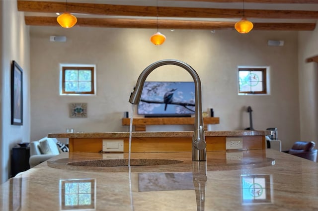 room details featuring beamed ceiling, light stone countertops, pendant lighting, and a sink