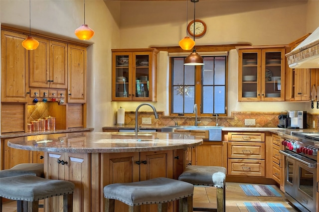 kitchen with a sink, a kitchen breakfast bar, backsplash, and range with two ovens