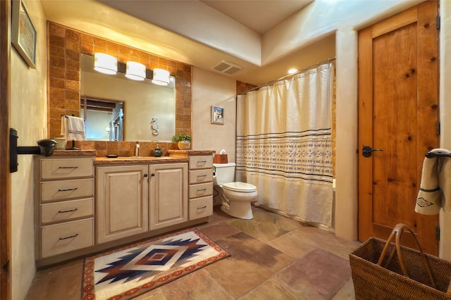 bathroom with visible vents, shower / bath combo with shower curtain, vanity, toilet, and stone finish flooring