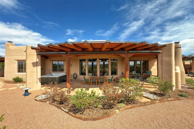 back of house with a hot tub, a patio, and an outdoor hangout area