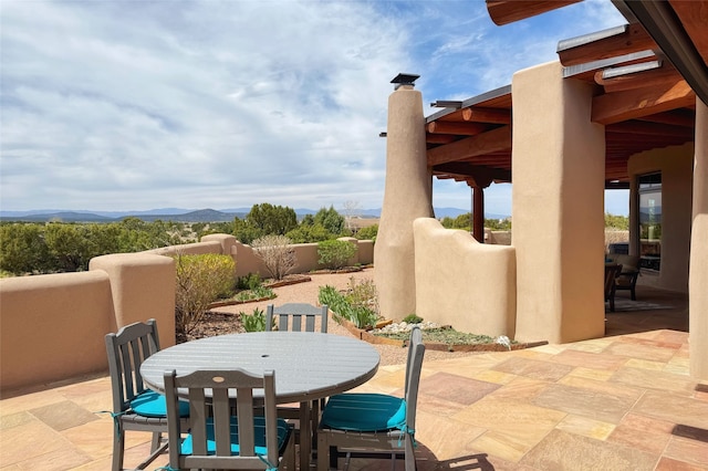 view of patio featuring fence, a mountain view, and outdoor dining space