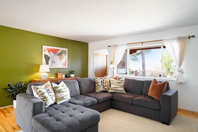 living room featuring a textured ceiling, baseboards, and wood finished floors