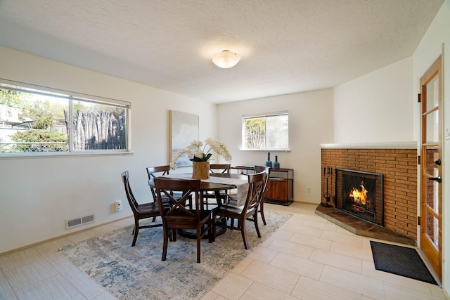 dining space featuring a textured ceiling, visible vents, and a fireplace