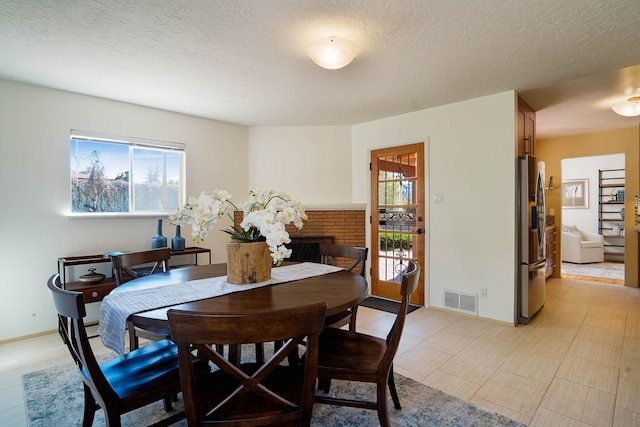 dining room featuring visible vents, a textured ceiling, baseboards, and a healthy amount of sunlight