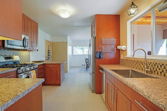 kitchen featuring light countertops, appliances with stainless steel finishes, decorative backsplash, and a sink