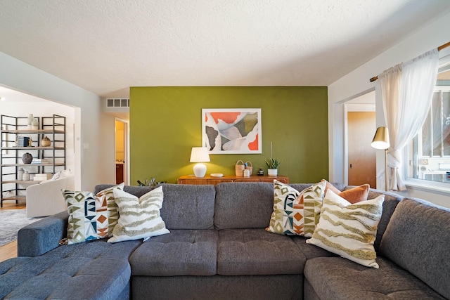 living area featuring a textured ceiling, visible vents, and wood finished floors