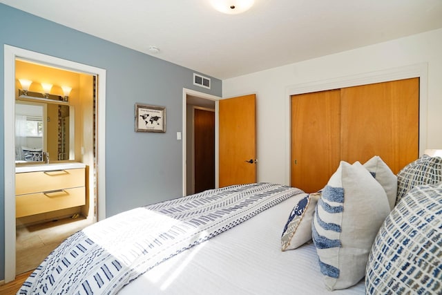 bedroom featuring connected bathroom, visible vents, and a closet