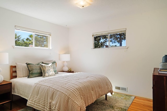 bedroom with visible vents, wood finished floors, and multiple windows