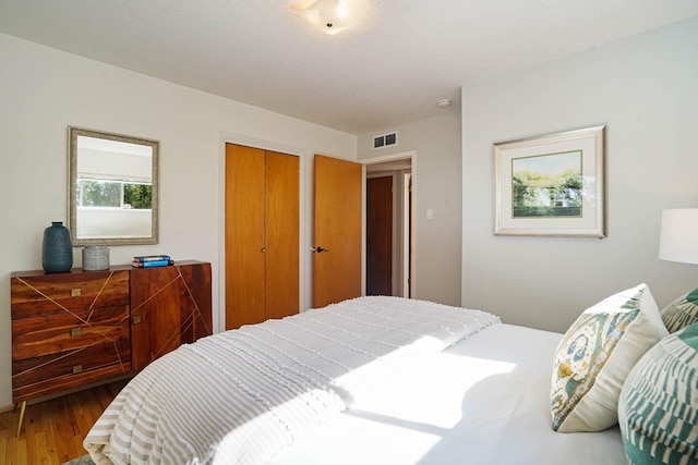 bedroom featuring a closet, wood finished floors, and visible vents