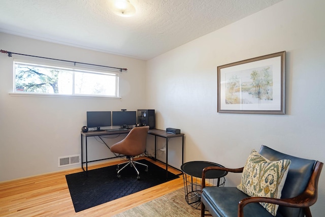office featuring a textured ceiling, wood finished floors, and visible vents