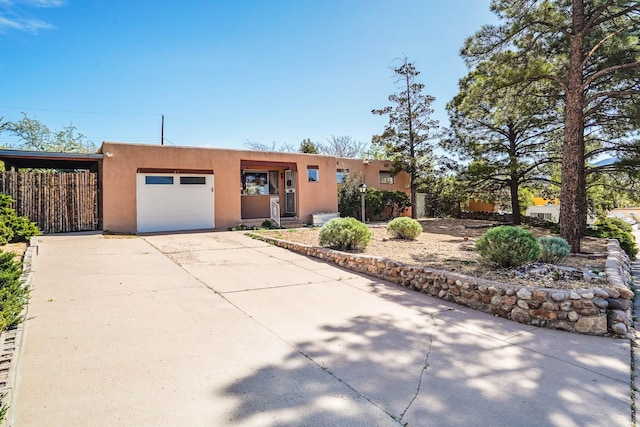 pueblo-style home featuring an attached garage, stucco siding, and concrete driveway