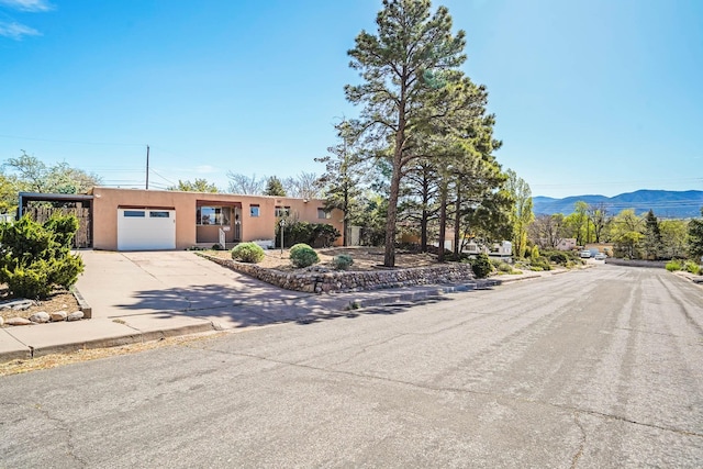 view of front of home with a garage, a mountain view, stucco siding, and driveway