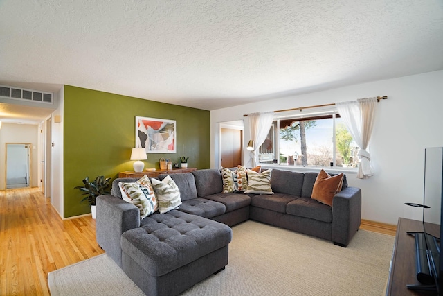 living room featuring visible vents, a textured ceiling, and baseboards