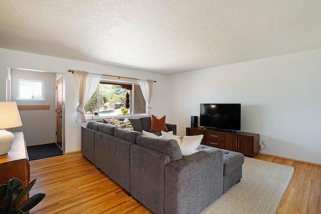 living area featuring light wood-style floors, plenty of natural light, and a textured ceiling