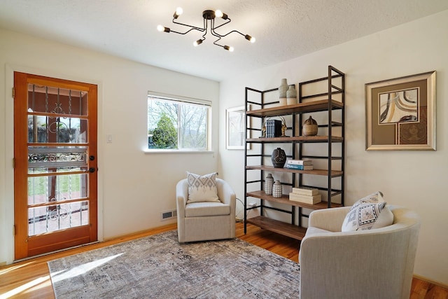 sitting room featuring a notable chandelier, wood finished floors, and visible vents