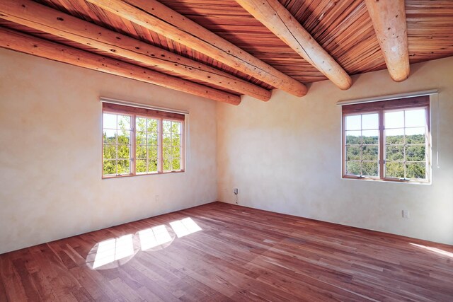empty room with wooden ceiling, a wealth of natural light, beam ceiling, and wood finished floors