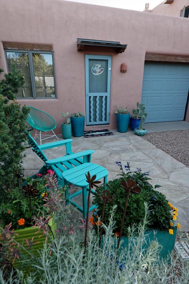 view of exterior entry with an attached garage and stucco siding
