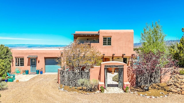 pueblo-style house with a garage, stucco siding, and driveway